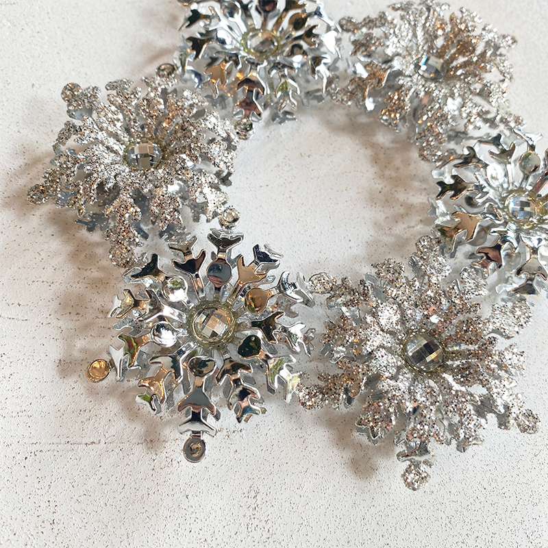 シルバーのラメやストーンが施された雪の結晶モチーフのオーナメント。クリスマス装飾やツリーデコレーション、冬の空間装飾に最適。